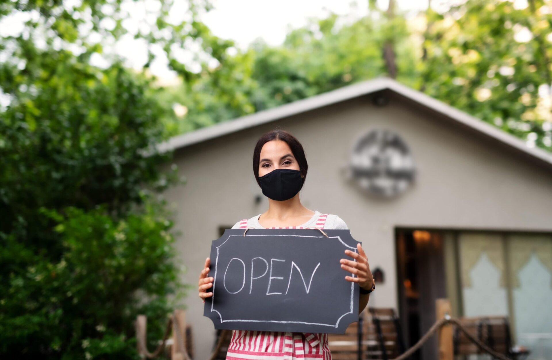 young woman with face mask working in cafe holding 2C44SAC min